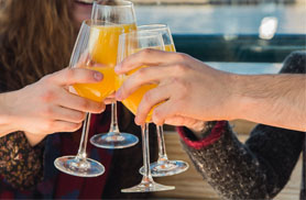 Friends clinking mimosas aboard the yacht Northern Lights for a Boston Brunch Cruise